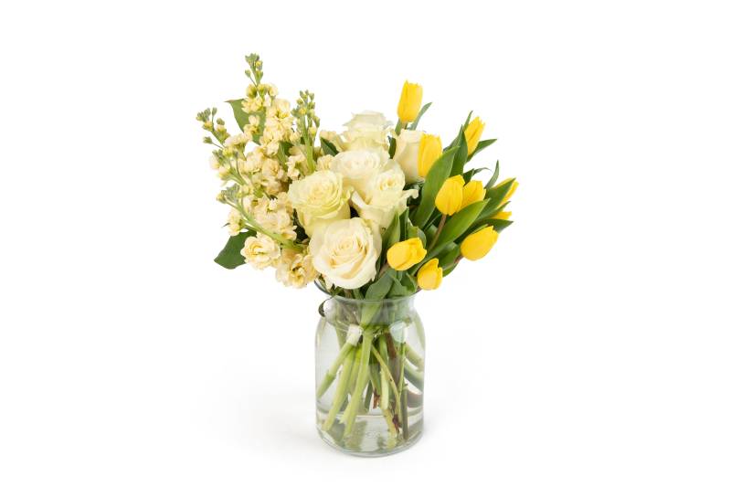 White roses and yellow tulips in a glass vase